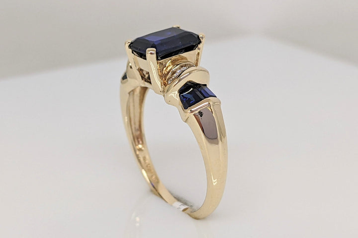 10K LAB CREATED SAPPHIRE EMERALD CUT 6X8 WITH (4) BAGUETTE AND (8) DIAMOND .12CTW ESTATE RING 4.1 GRAMS